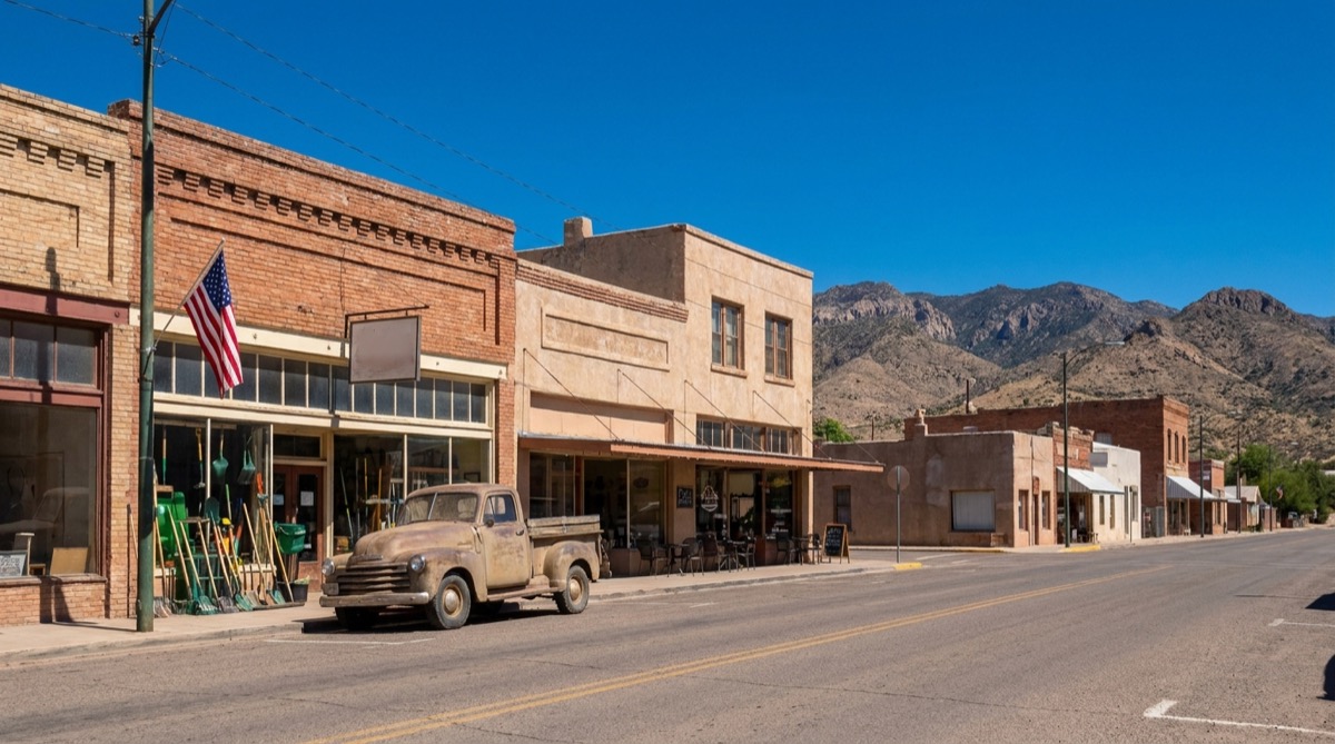 A small-town main street in southwest New Mexico with brick storefronts and mountains at the end of the road.
