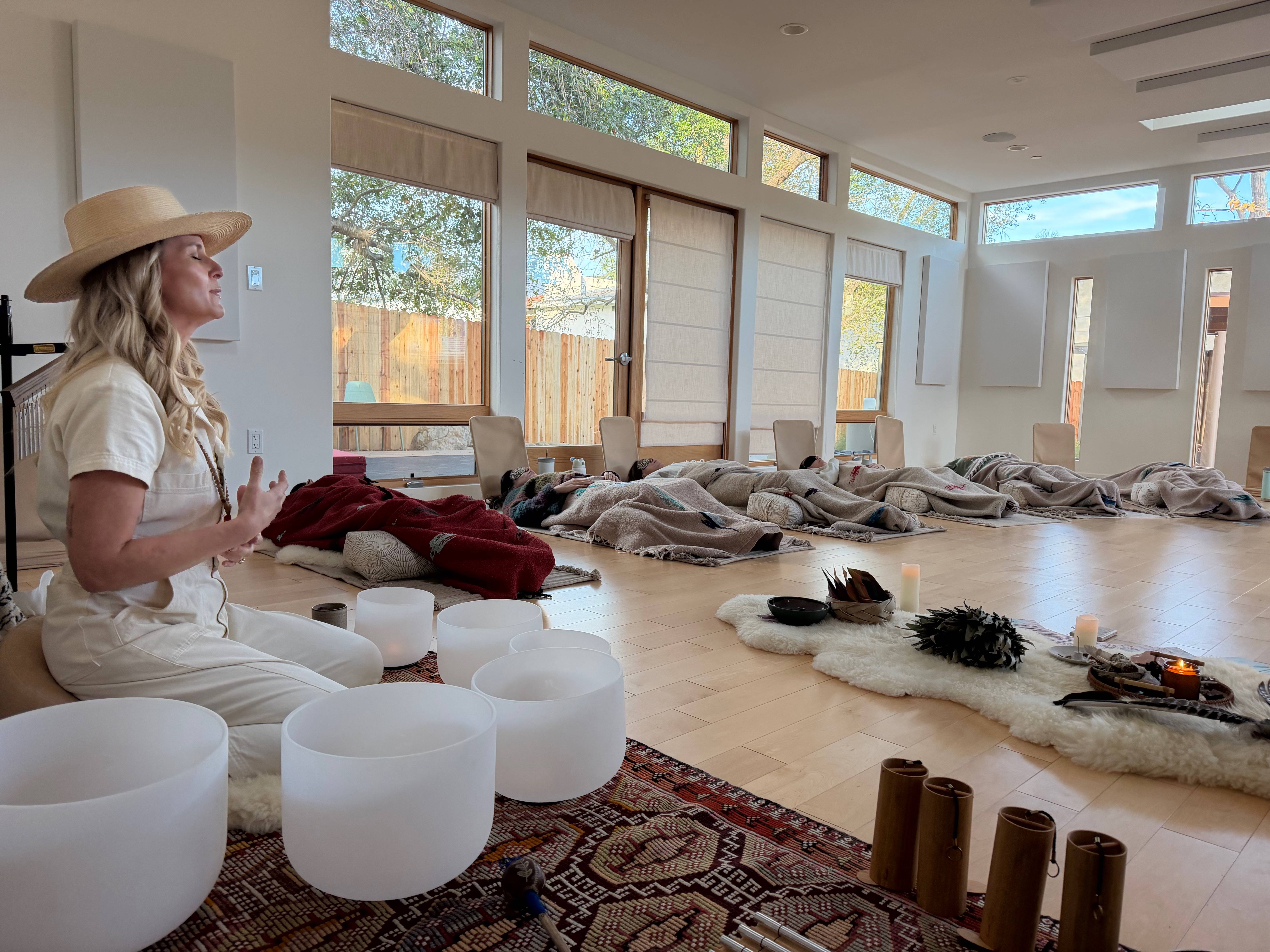 Kali May leading a sound bath breathwork journey with singing bowls