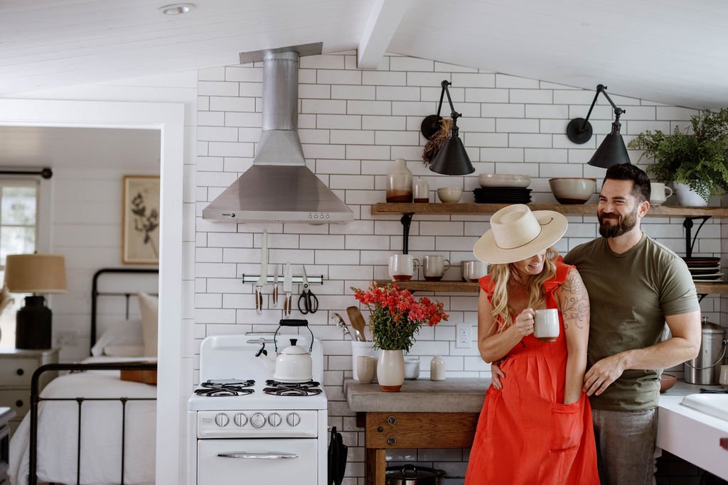 A couple sharing coffee from handmade ceramic mugs in a warm kitchen