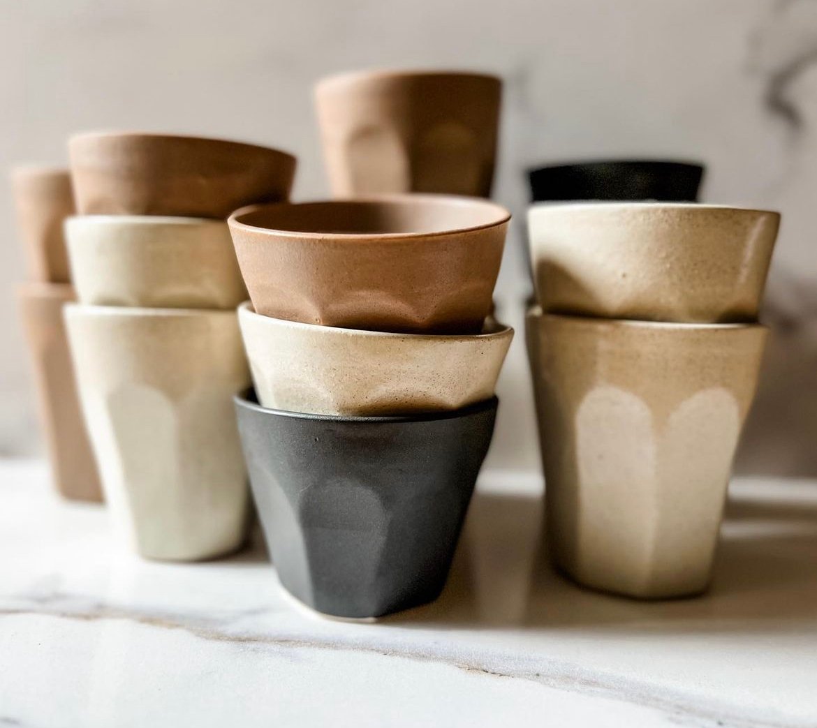 A stack of handmade ceramic tumblers in natural colors