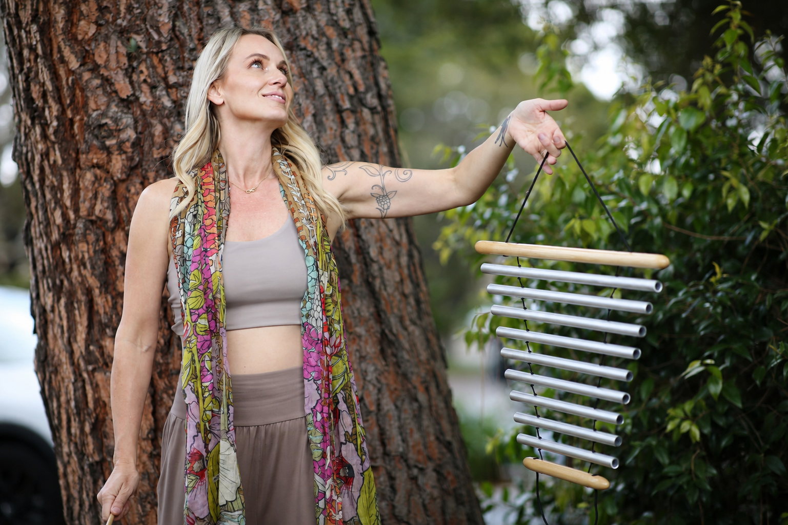 Kali May holding wind chimes beside a tree before ceremony