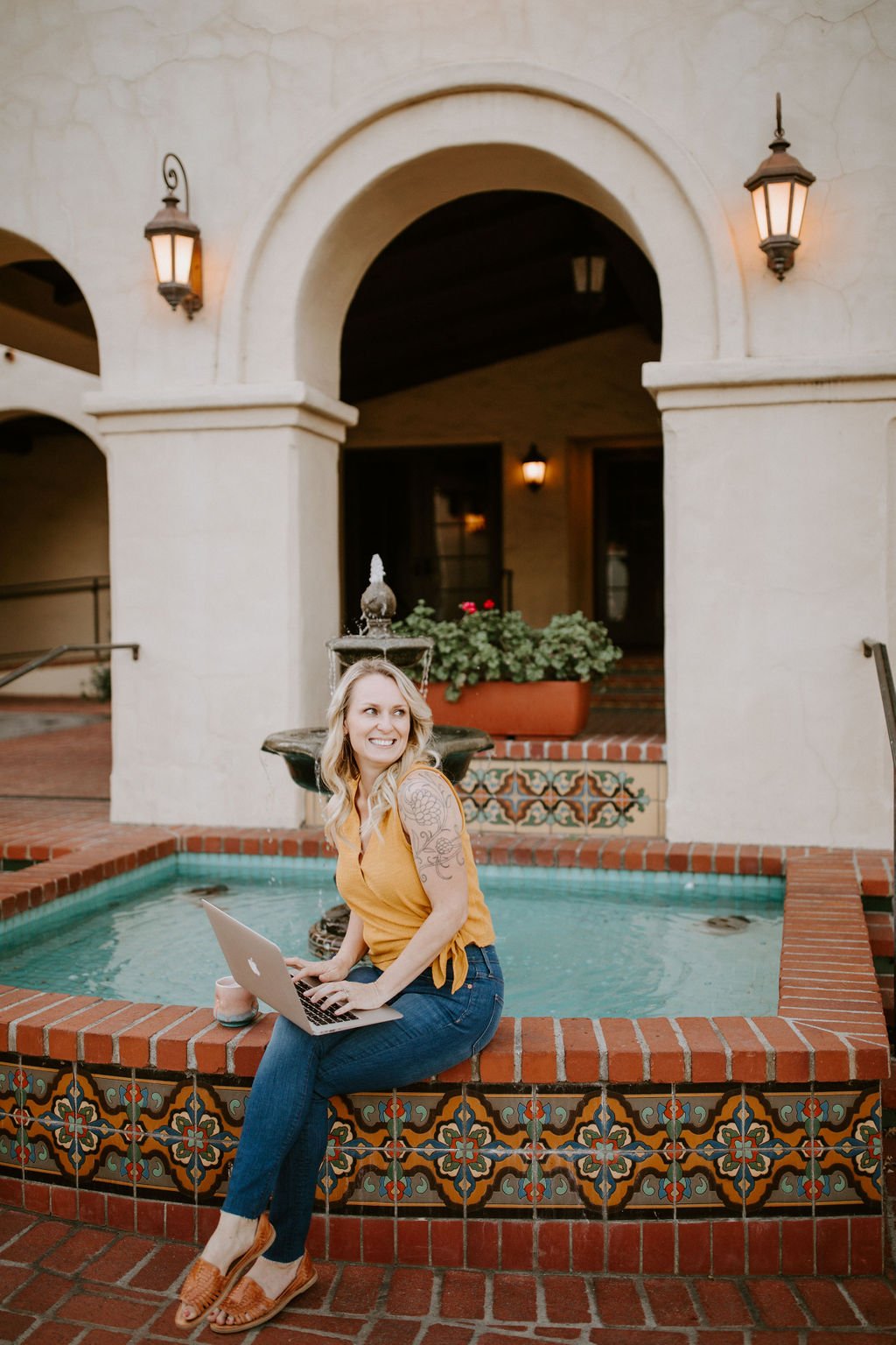 Kali working on her laptop beside an Ojai fountain