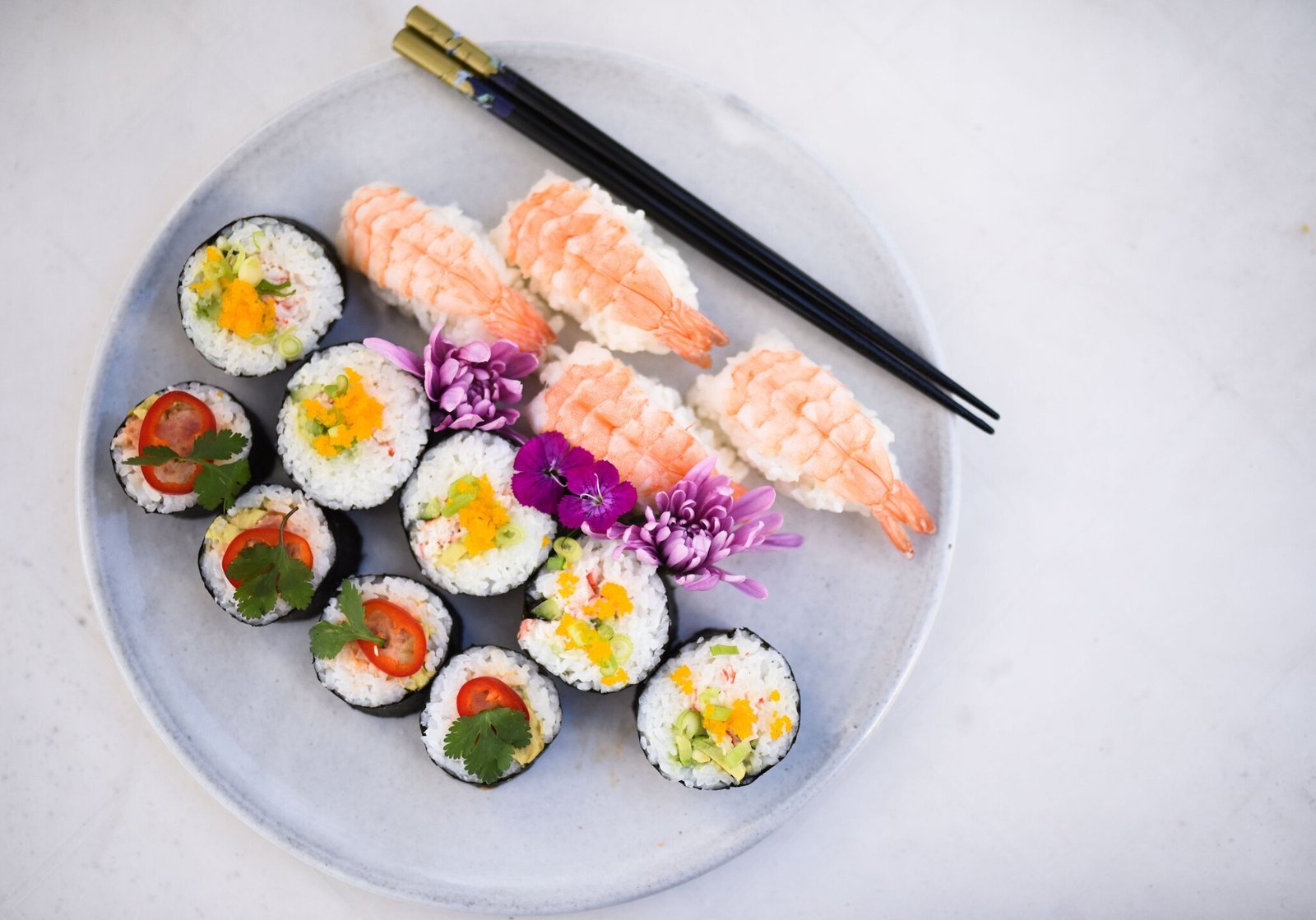 Soft grey Chief Peak Collection plate styled with sushi, chopsticks, and fresh flowers