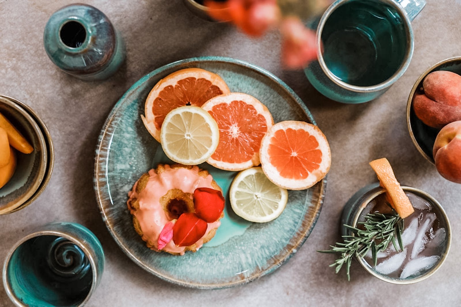 Glossy teal Topa Topa Collection dinnerware styled with citrus, cake, and drinks
